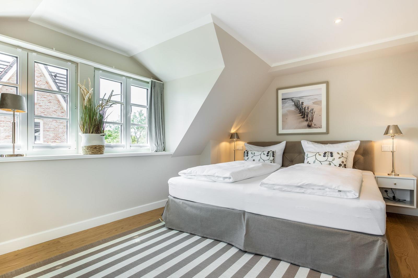 Schlafzimmer mit Doppelbett, Fenster und Wandbild.