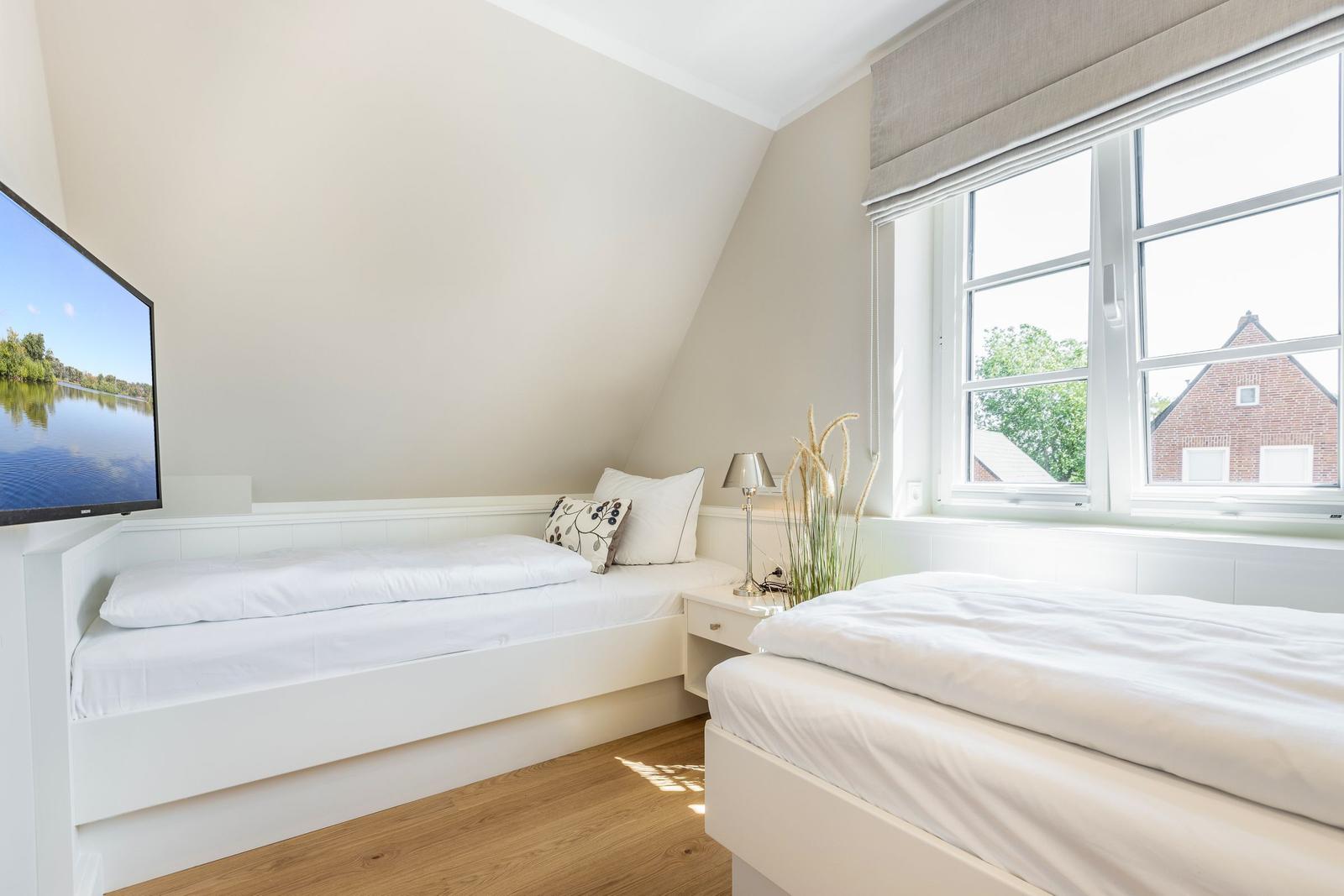 Zwei Betten in einem Schlafzimmer mit Fenster und Fernseher.