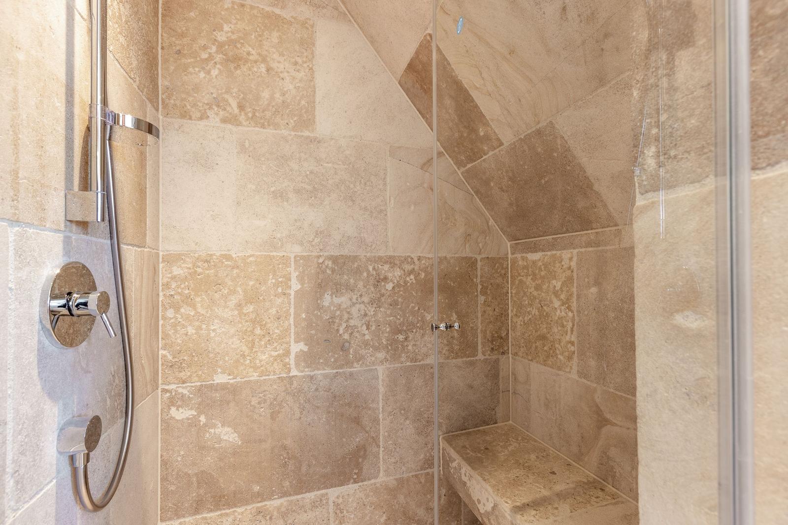 Dusche mit Steinwand und Sitzbank