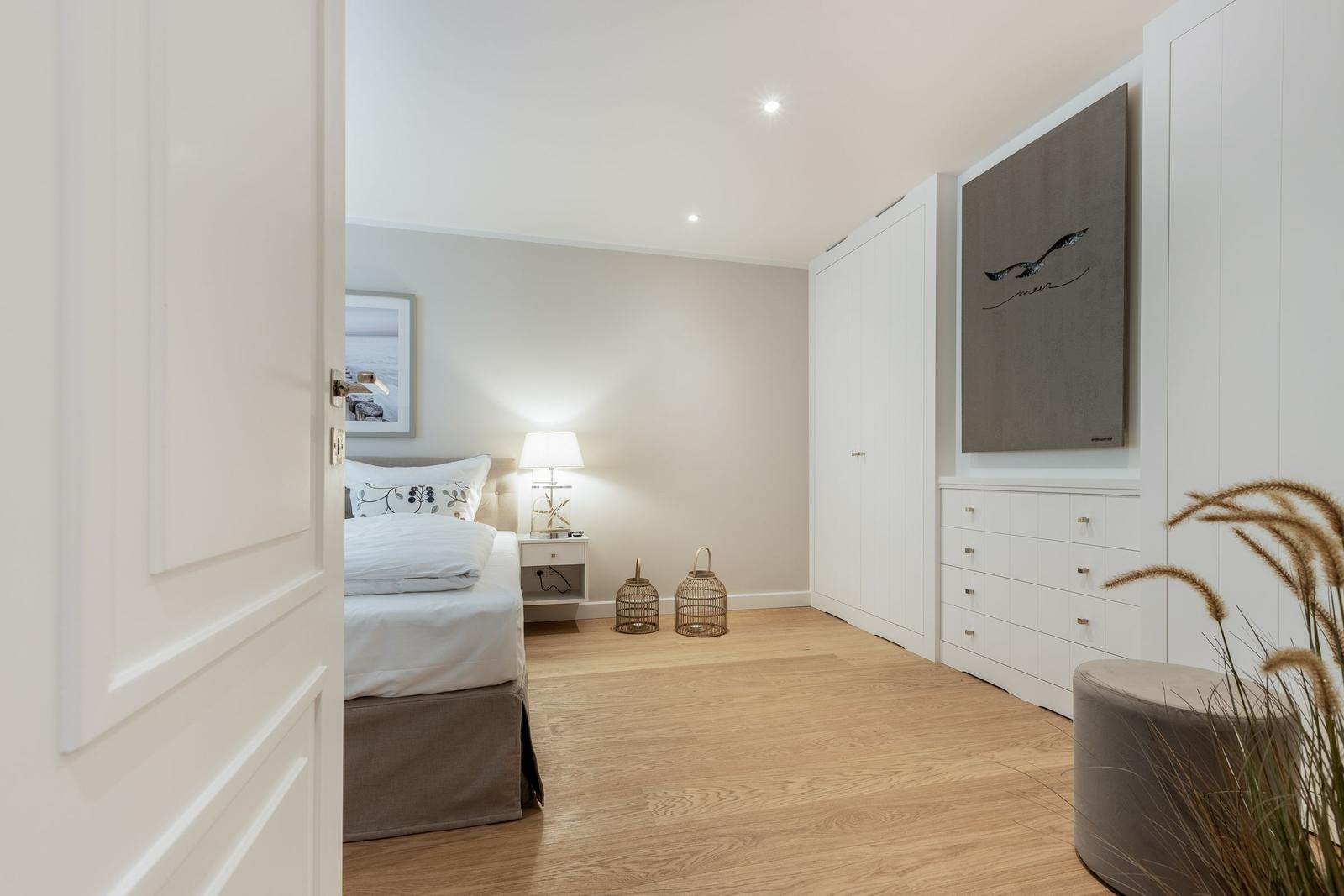 Schlafzimmer mit Bett, Nachttisch, Kleiderschrank und Wandbild.