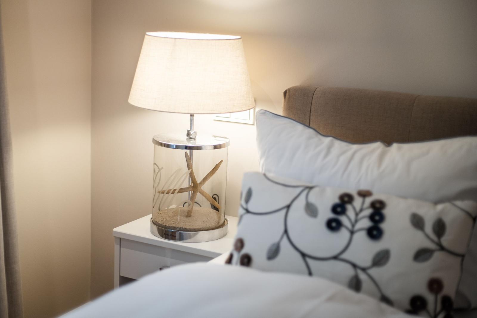 Schlafzimmer mit Nachttisch, Lampe und Kissen