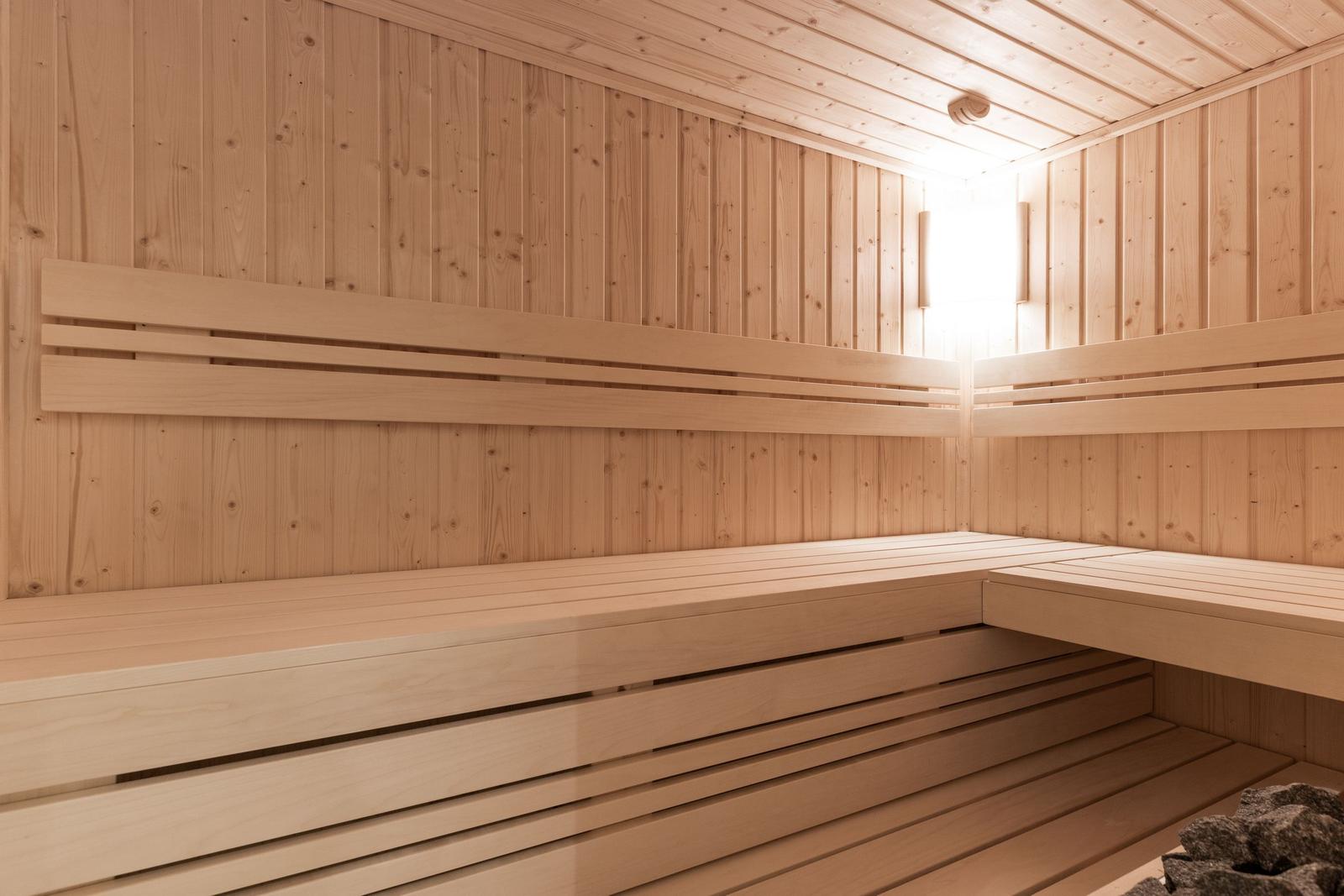 Holzsauna mit mehreren Sitzreihen und Stein im Ecke.