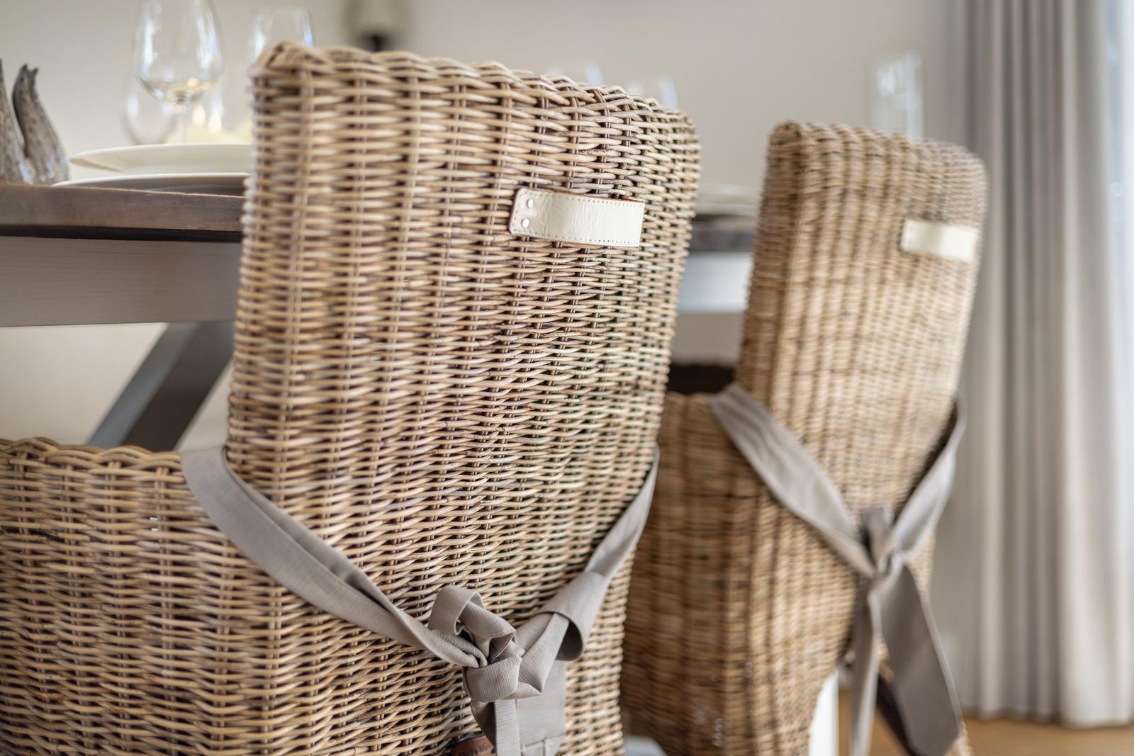 Zwei geflochtene Stühle mit grauen Bändern an einem Tisch