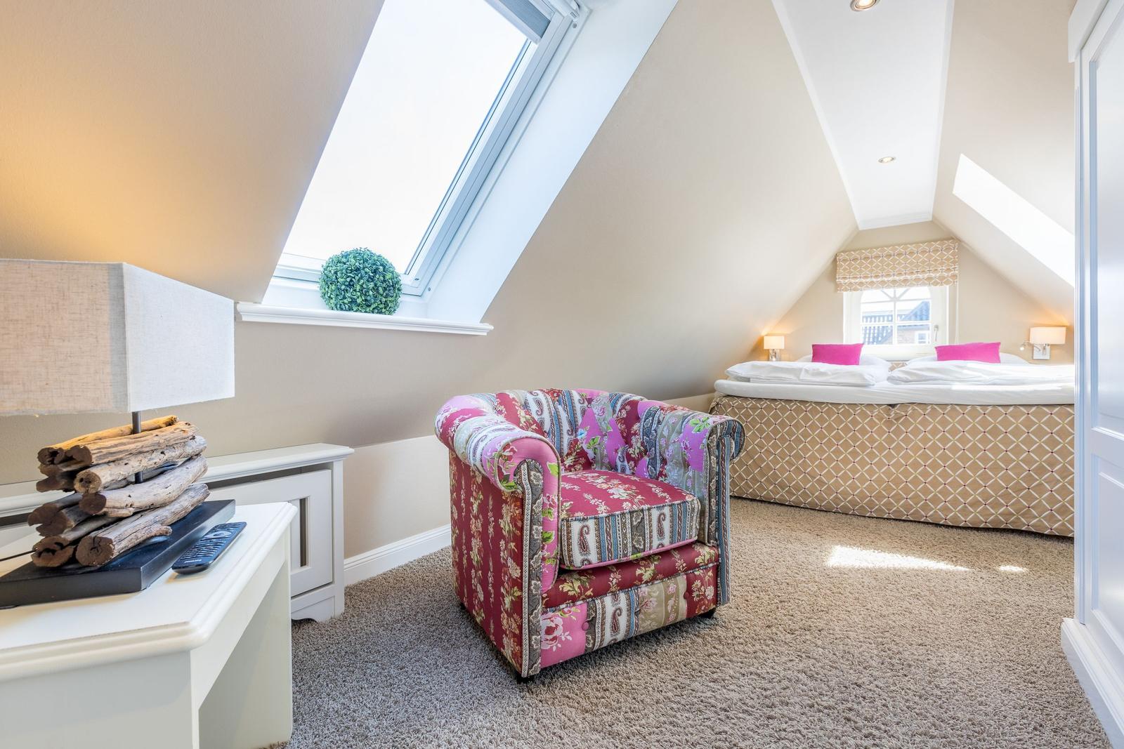 Attic room with bed, armchair, and skylight