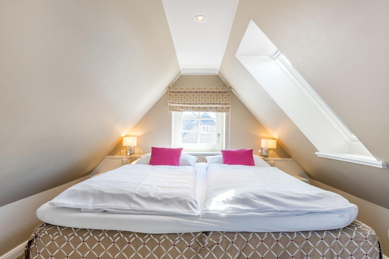 Bedroom with double bed, skylight, and window with roller blind.