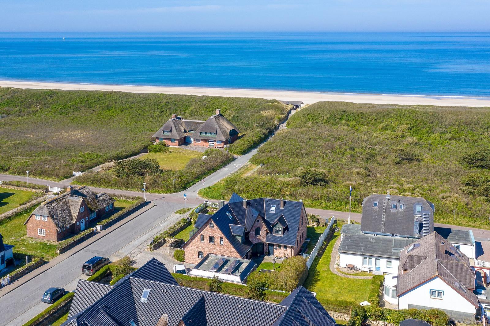 House with gable roof and view of beach and sea.