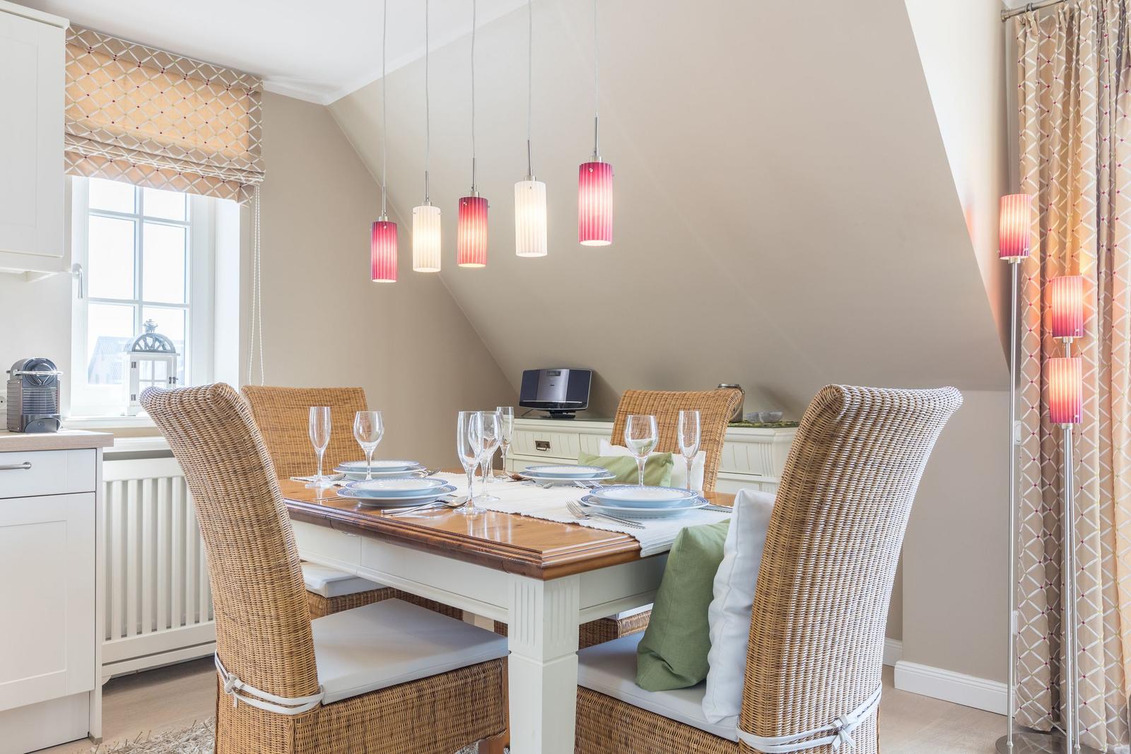 Dining room with table, chairs, and pendant lights under sloped ceiling