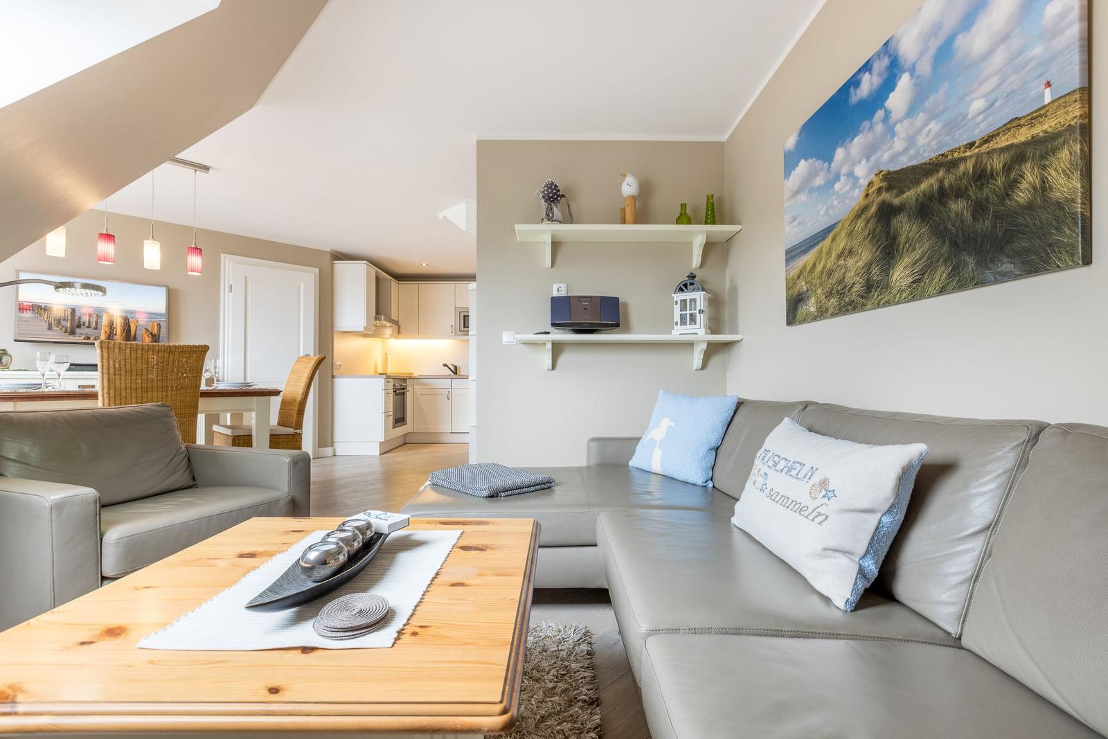 Wohnzimmer mit Sofa, Couchtisch und Küchenbereich im Hintergrund.