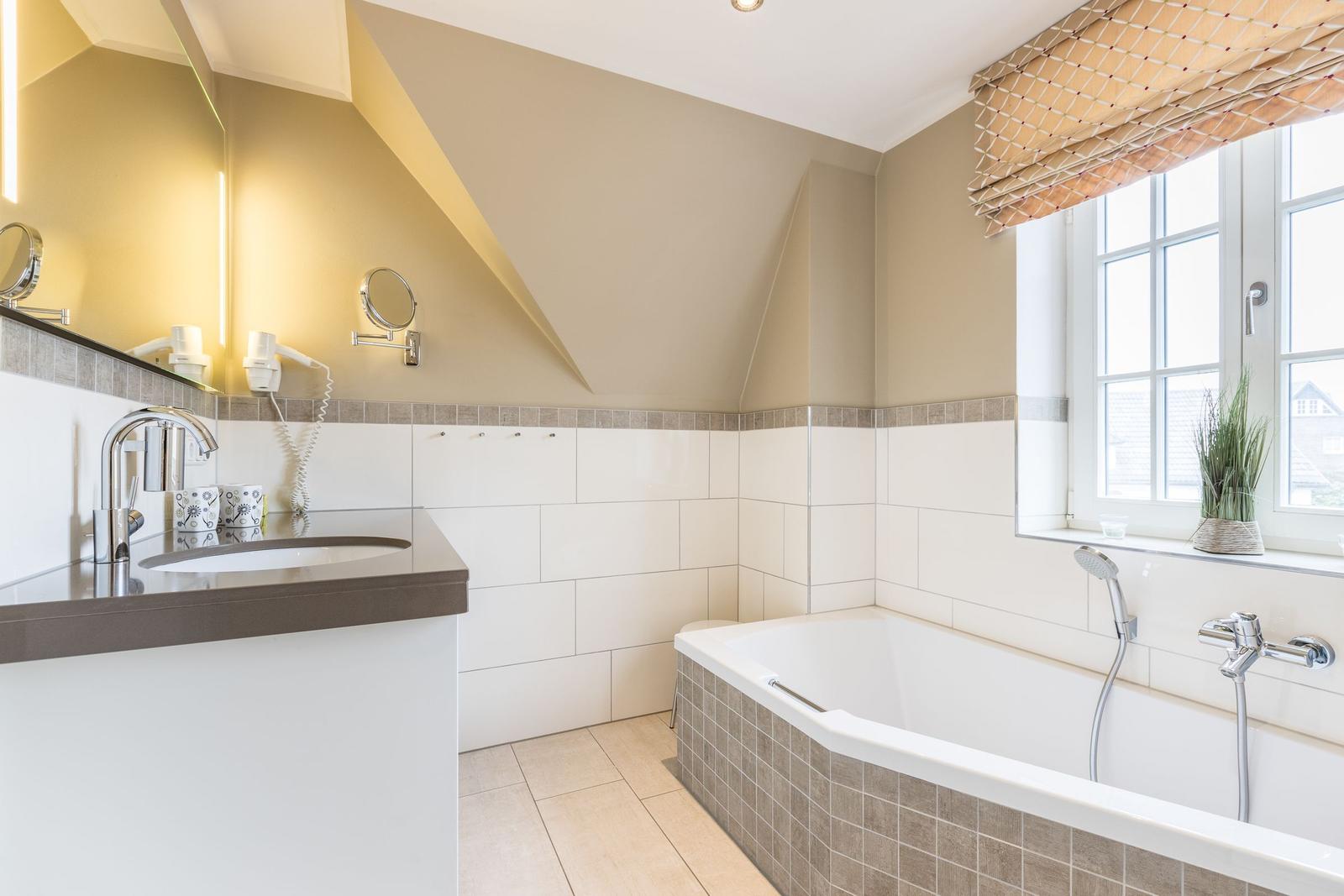 Badezimmer mit Badewanne, Waschbecken und Fenster