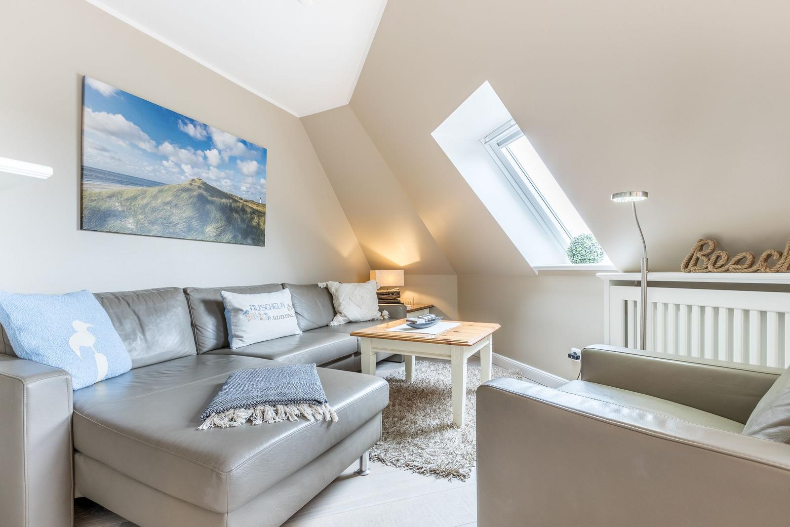 Wohnzimmer mit Sofa, Couchtisch und Dachfenster. Wandbild und Beleuchtung sichtbar.