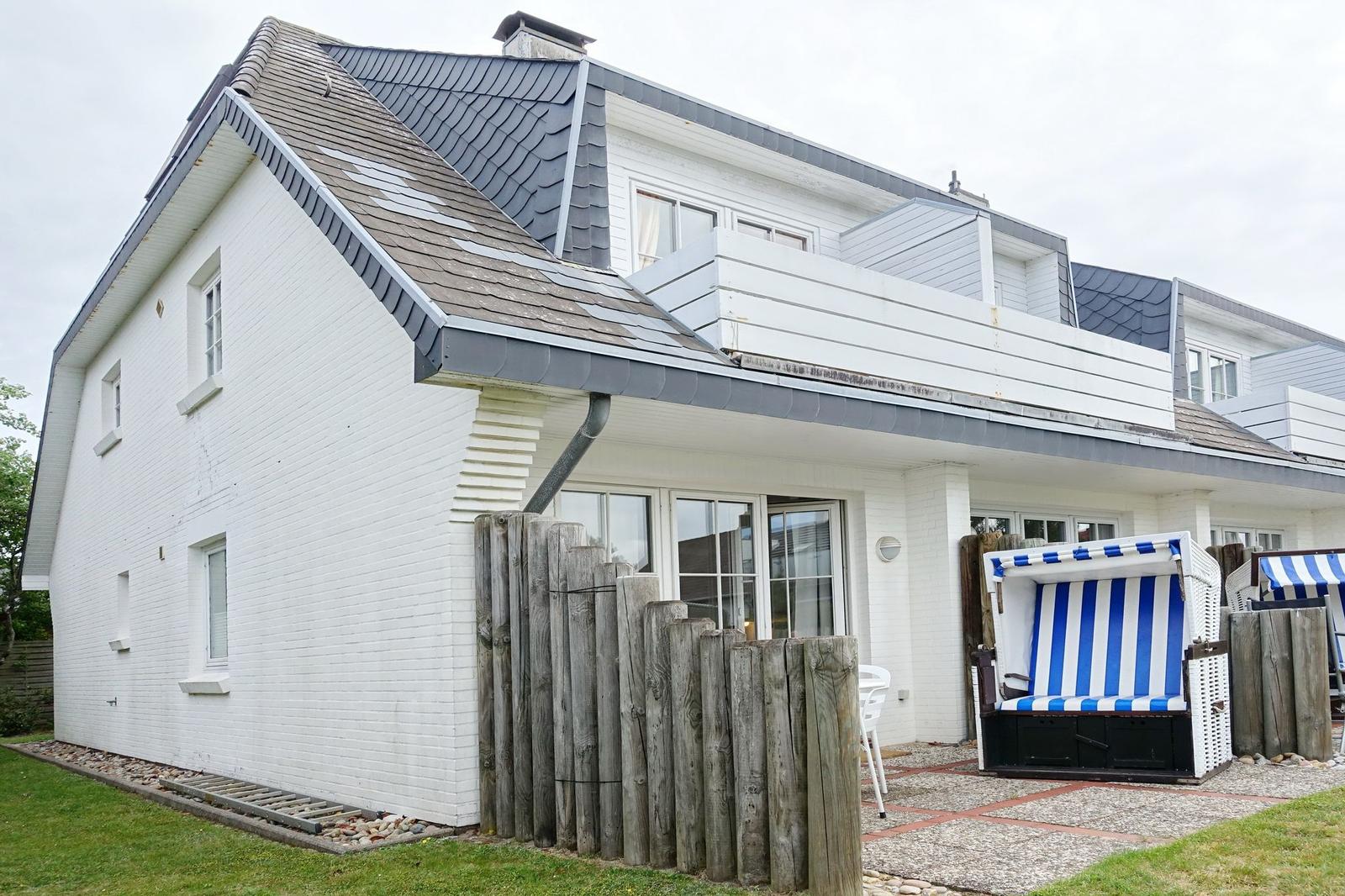 White house with balcony and beach chairs in the garden