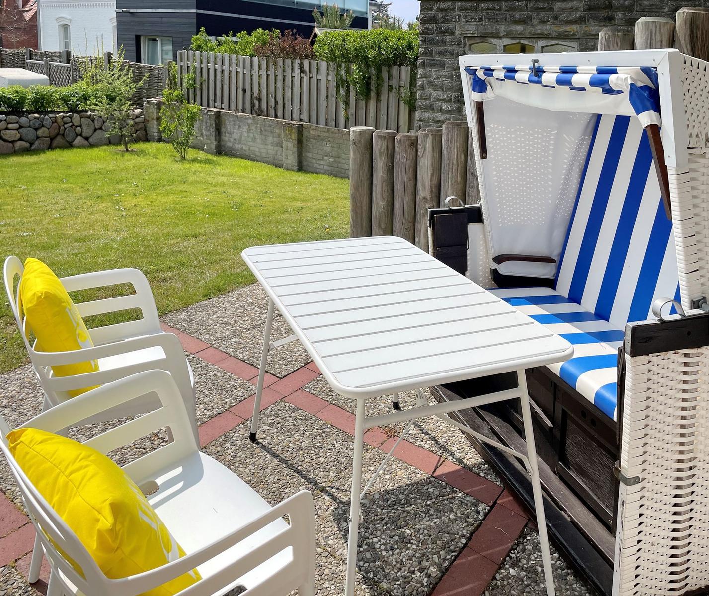 Backyard with garden, table, chairs, and beach chair.