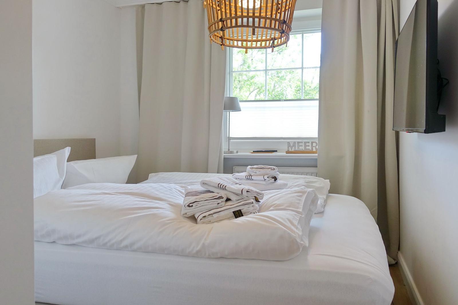 Bedroom with bed, window, and wall lamp