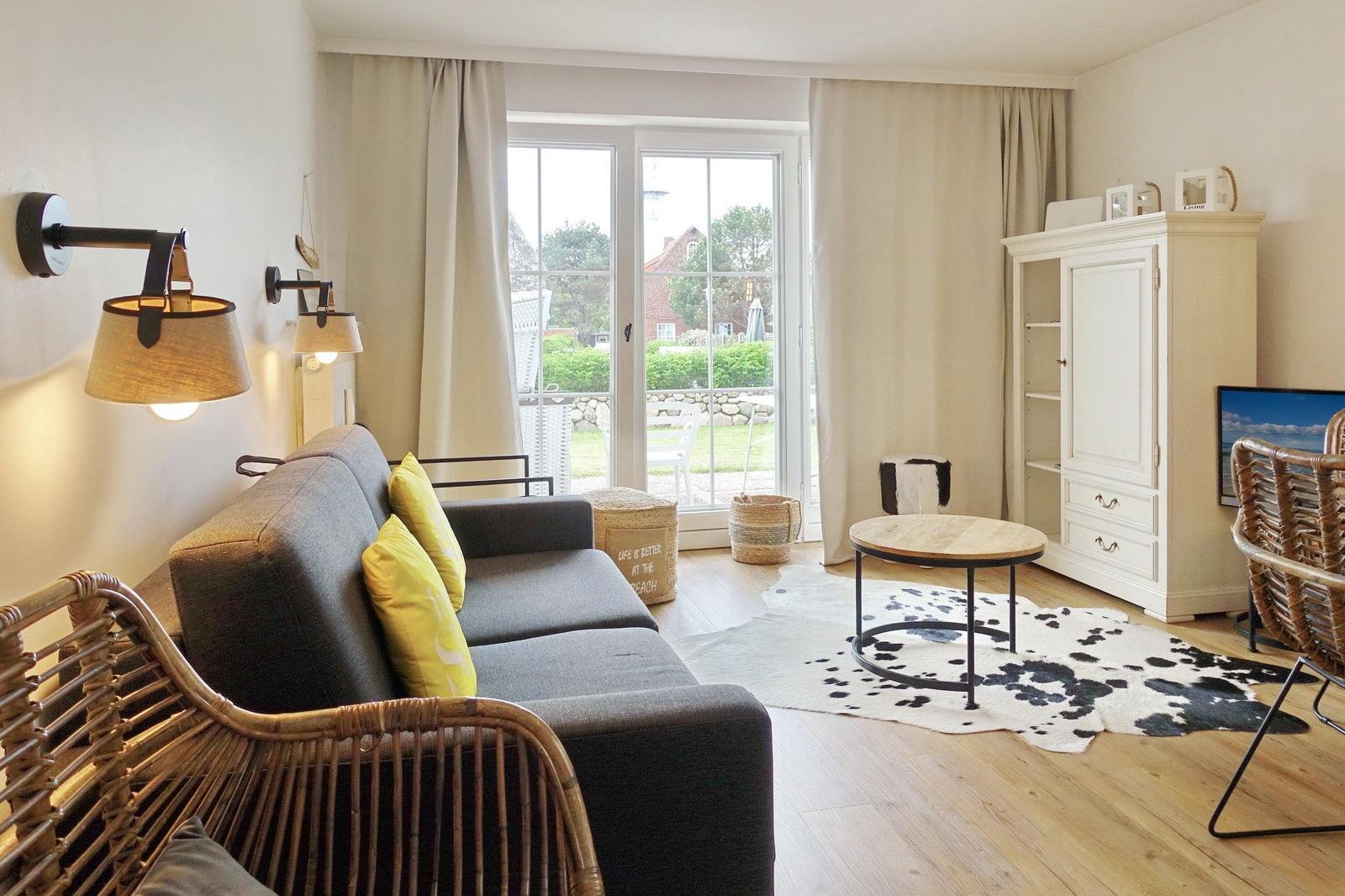 Living room with sofa, rattan chairs, and view to the terrace.