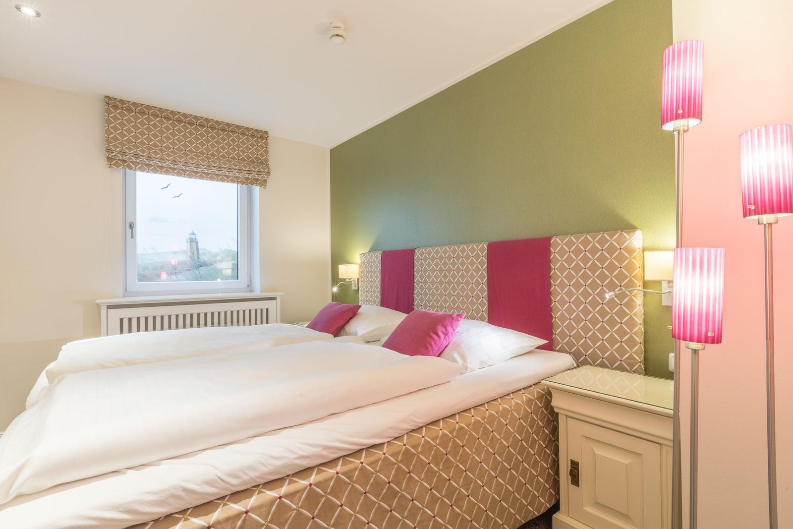 Schlafzimmer mit Doppelbett, Fenster mit Blick und Stehlampe.