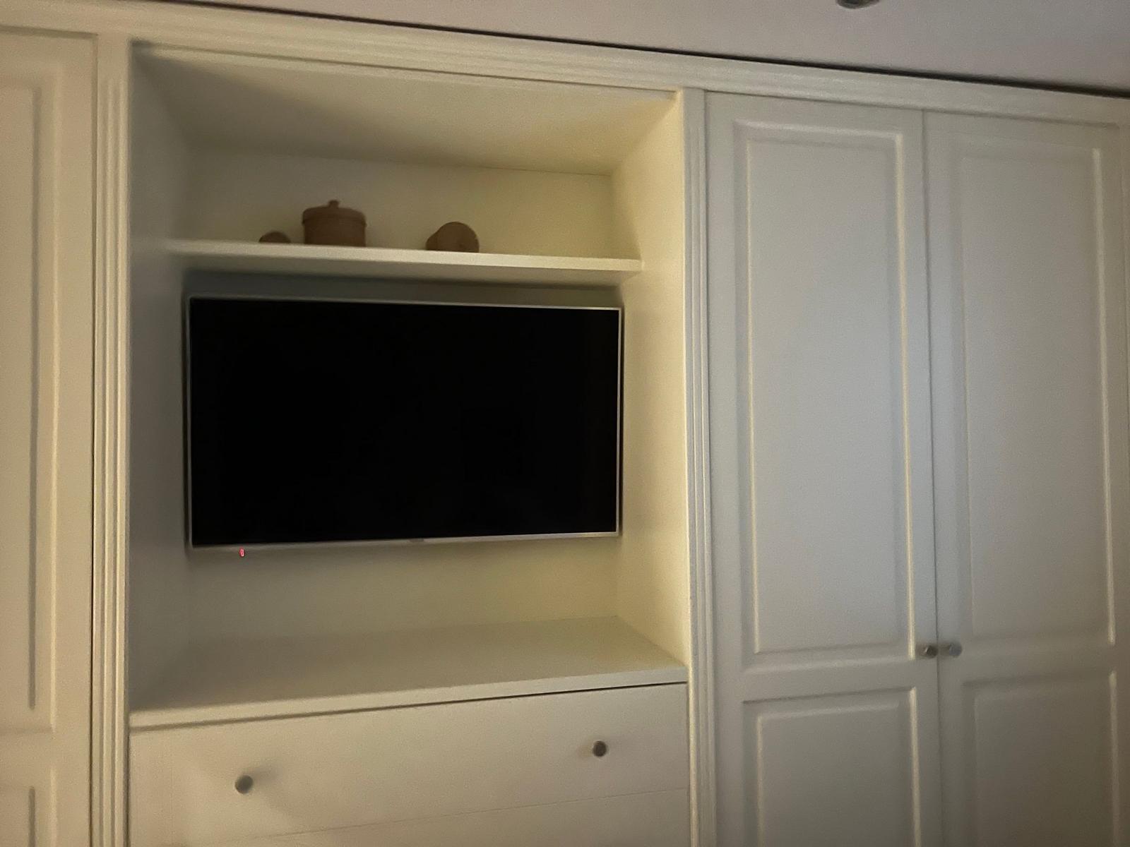Ein eingebautes TV-Fach mit Schublade und dekorativen Gegenständen.