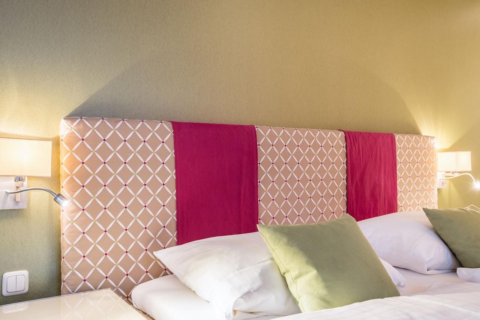 Schlafzimmer mit Bett, Kopfteil und Wandlampen.