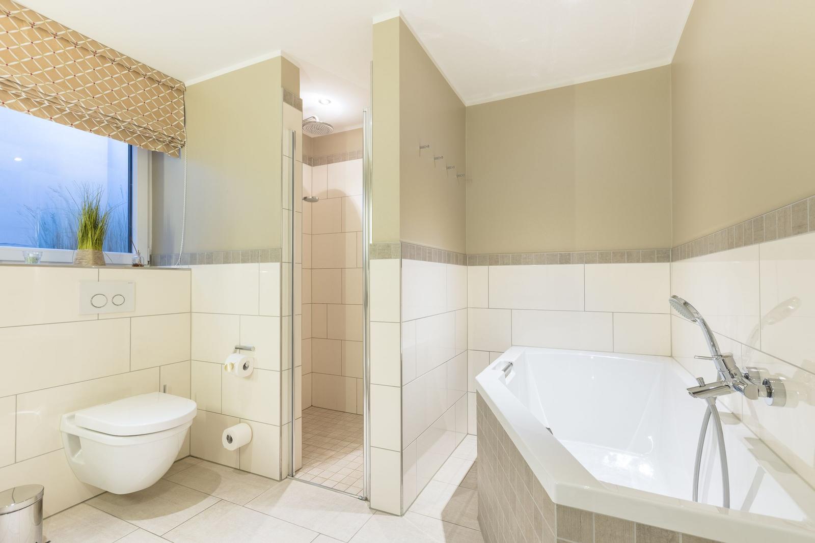 Bad mit Dusche, Badewanne und Toilette. Fenster mit Rollladen.