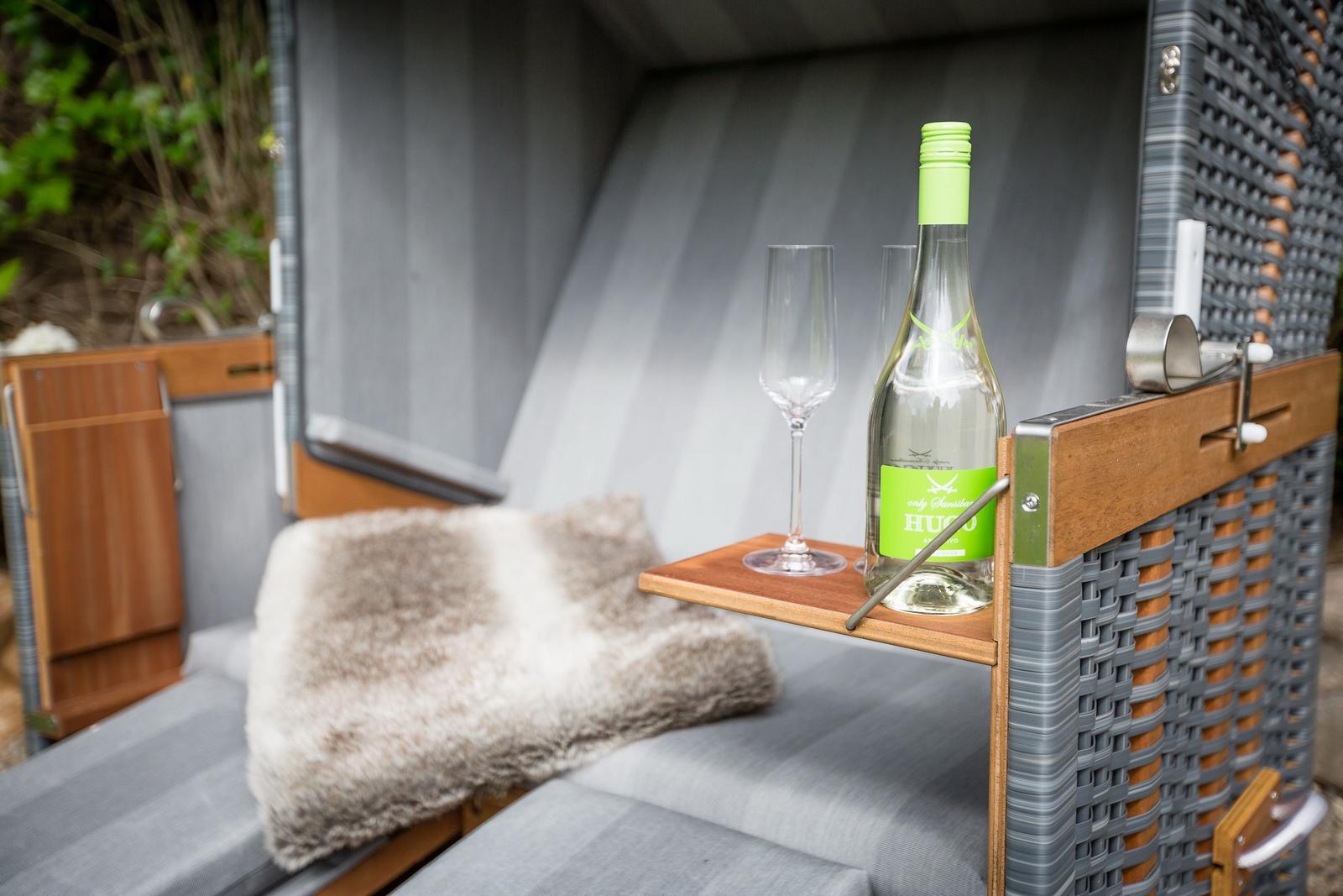 Outdoor lounge with bottle and glasses on a table.