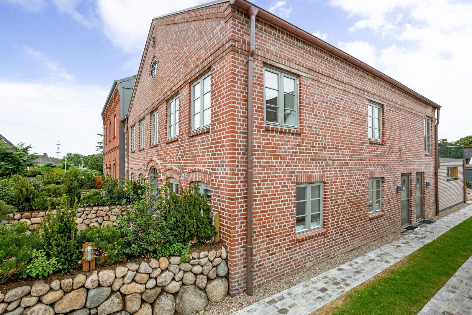 Red brick house with garden and stone wall.