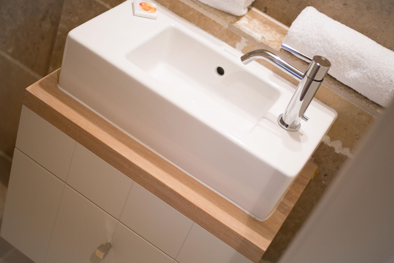 Sink with faucet on wooden top and white cabinet.