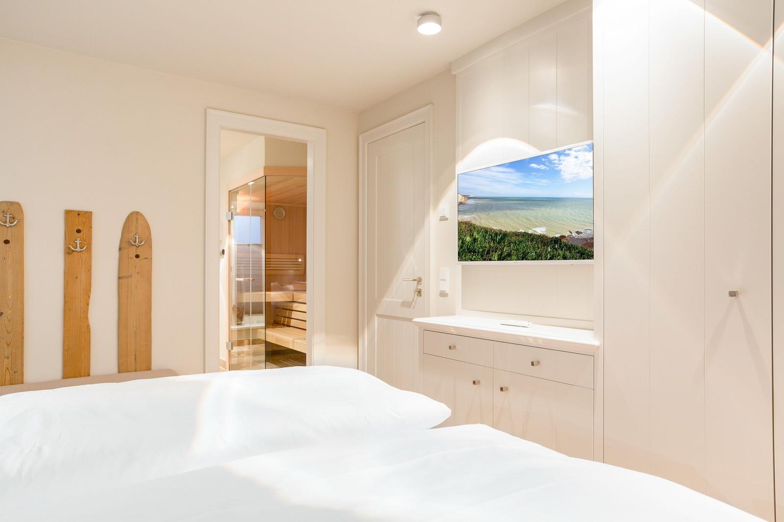 Bedroom with bed, TV, and view into the sauna.