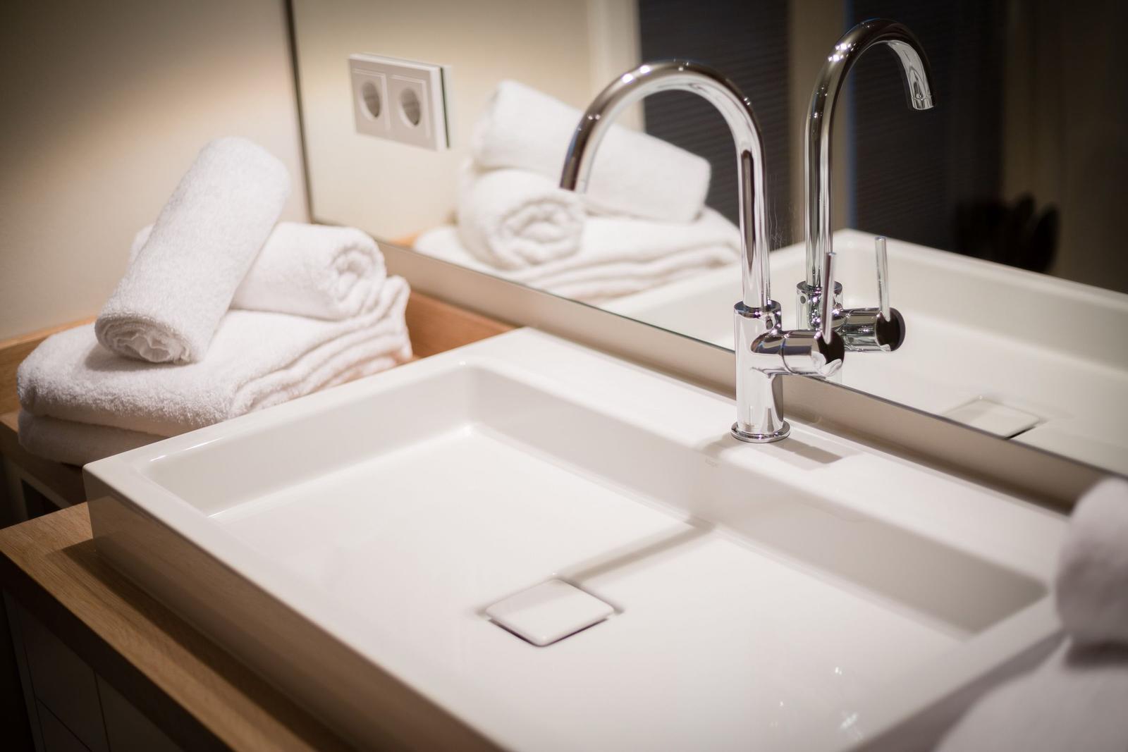 Sink with mirror and towels on wooden surface