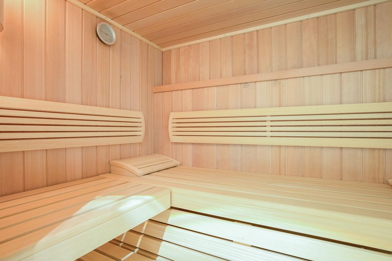 Sauna with wooden benches and wall thermometer