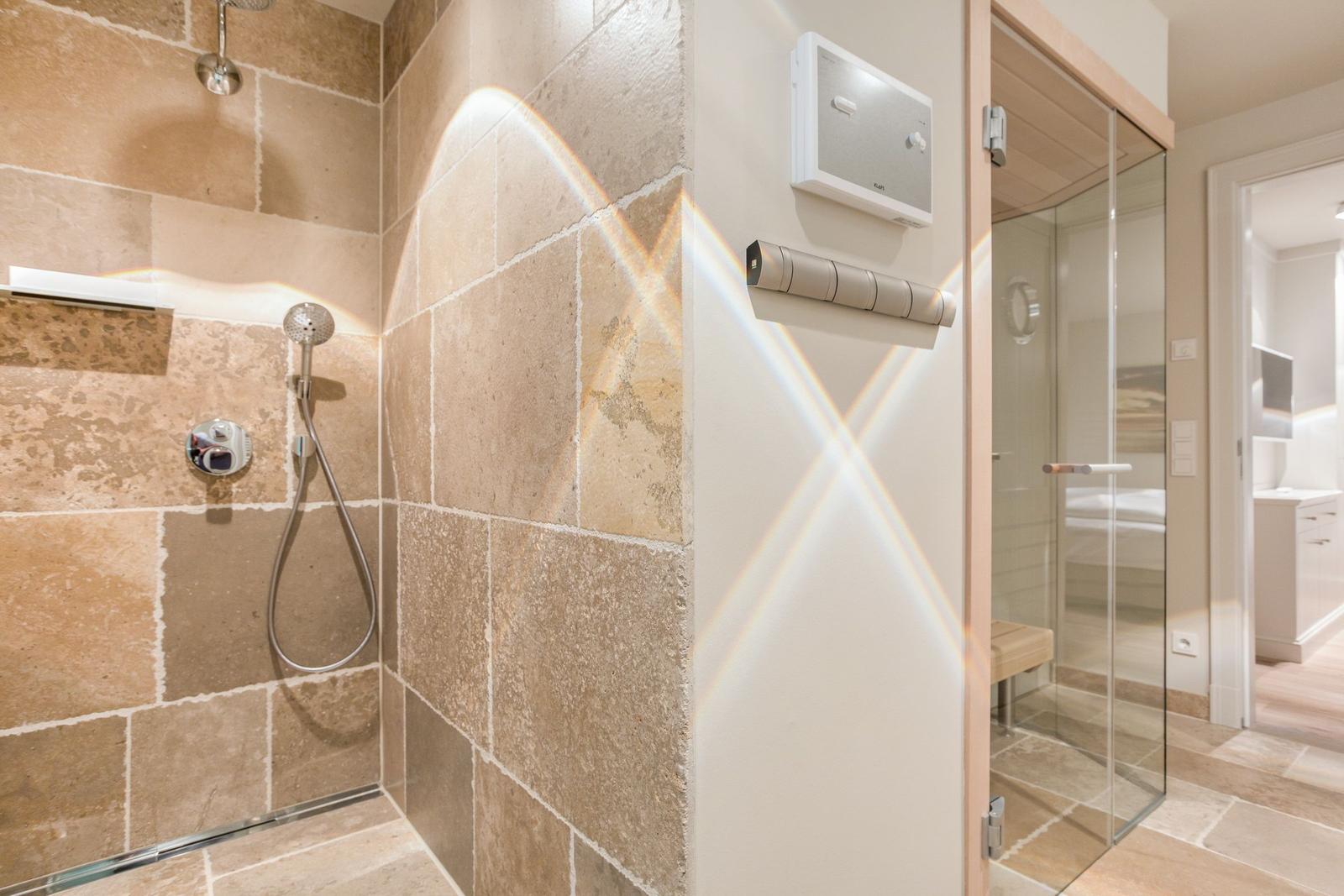 Shower with stone wall and glass wall to sauna