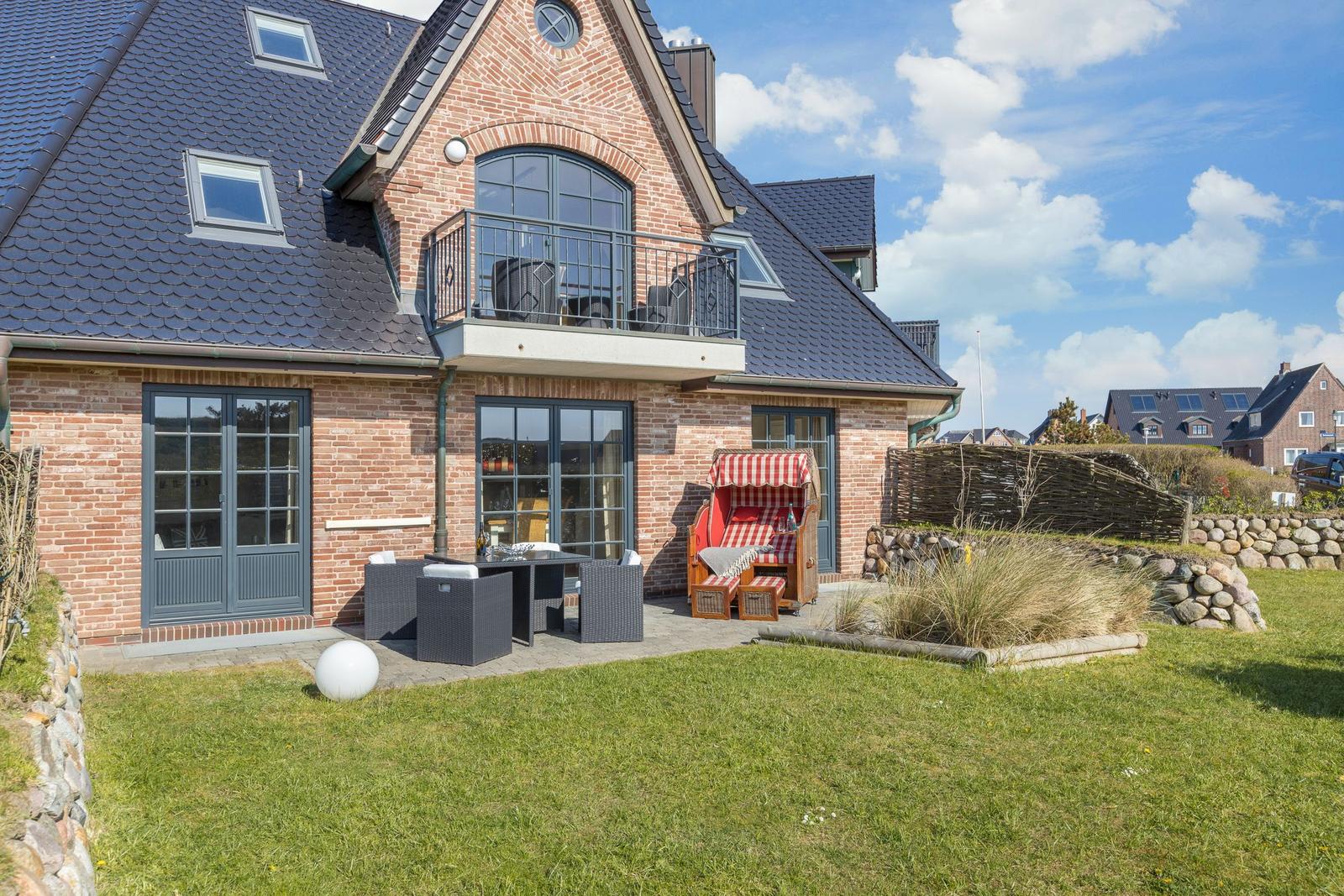 Haus mit Balkon, Garten und Liegestuhl im Freien.