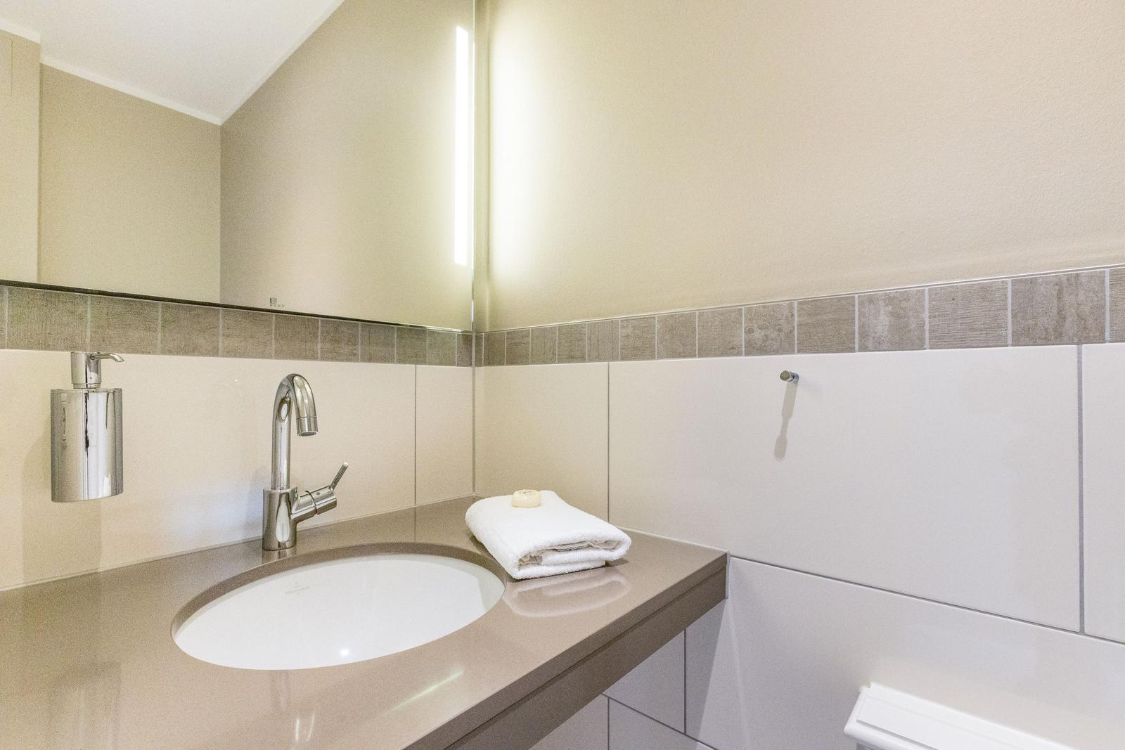 Bad mit Waschbecken, Spiegel und Handtuch