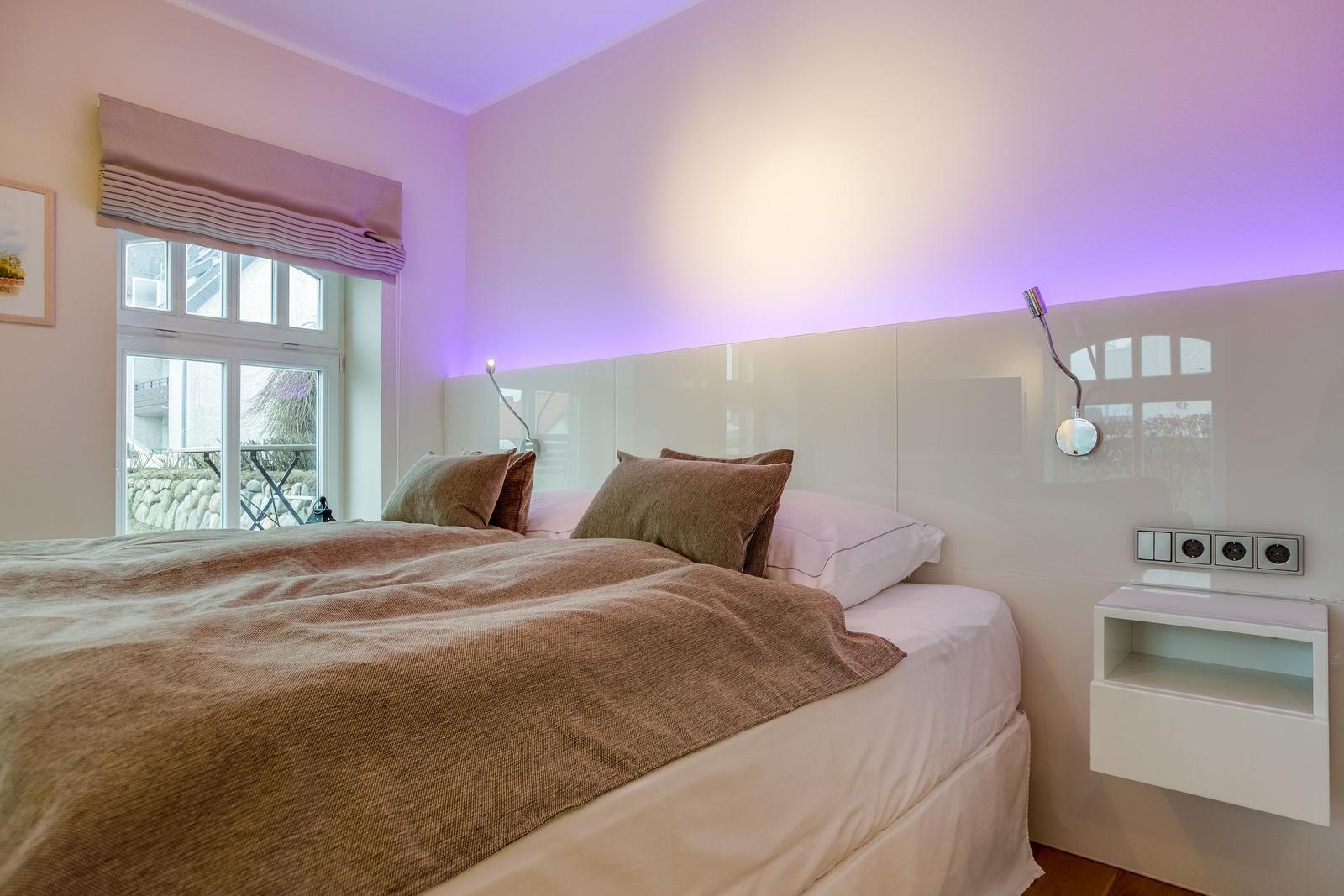 Bedroom with bed, window, and modern lighting.