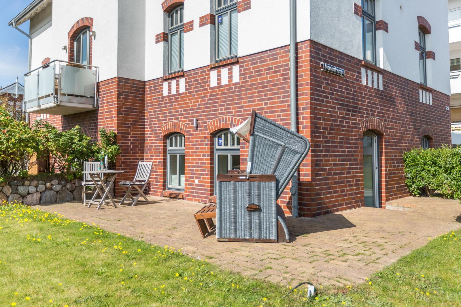 Terrace with lounge chair and table in front of a brick house.