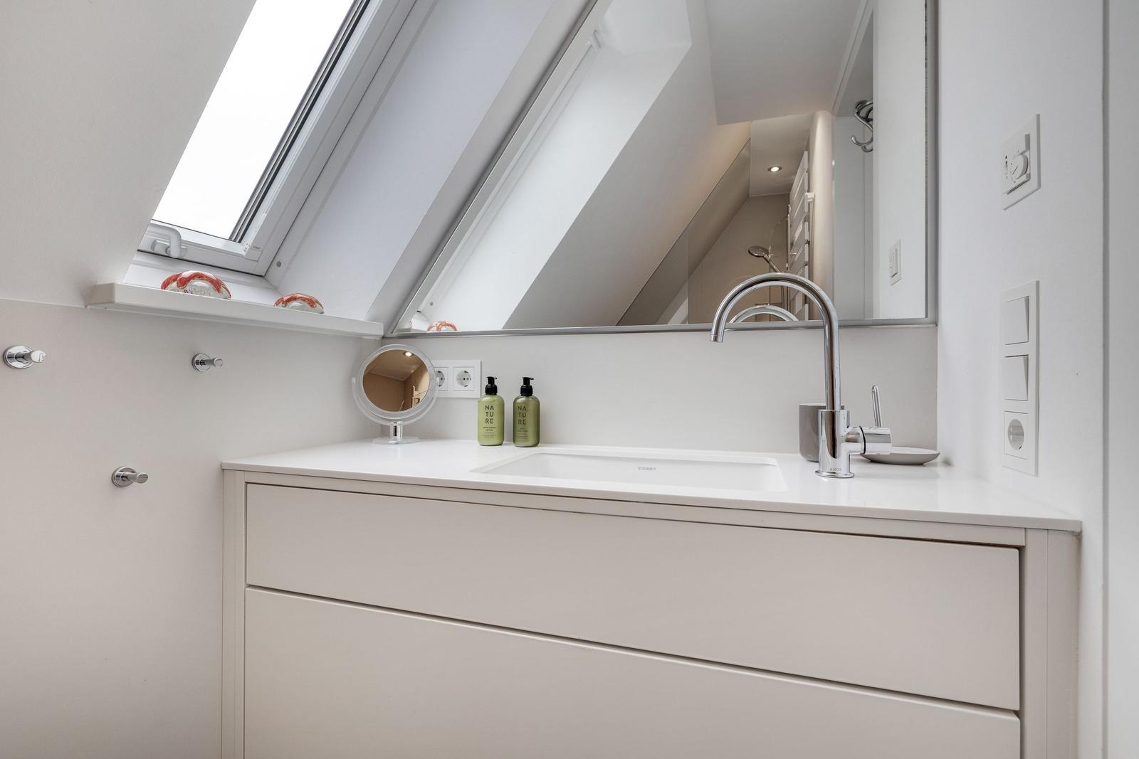 Badezimmer mit Waschbecken, Spiegel und Dachfenster