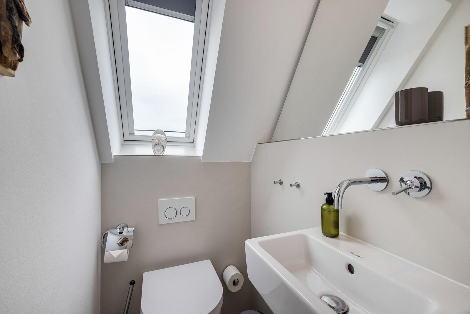 Badezimmer mit Dusche, Waschbecken und Toilette unter Dach