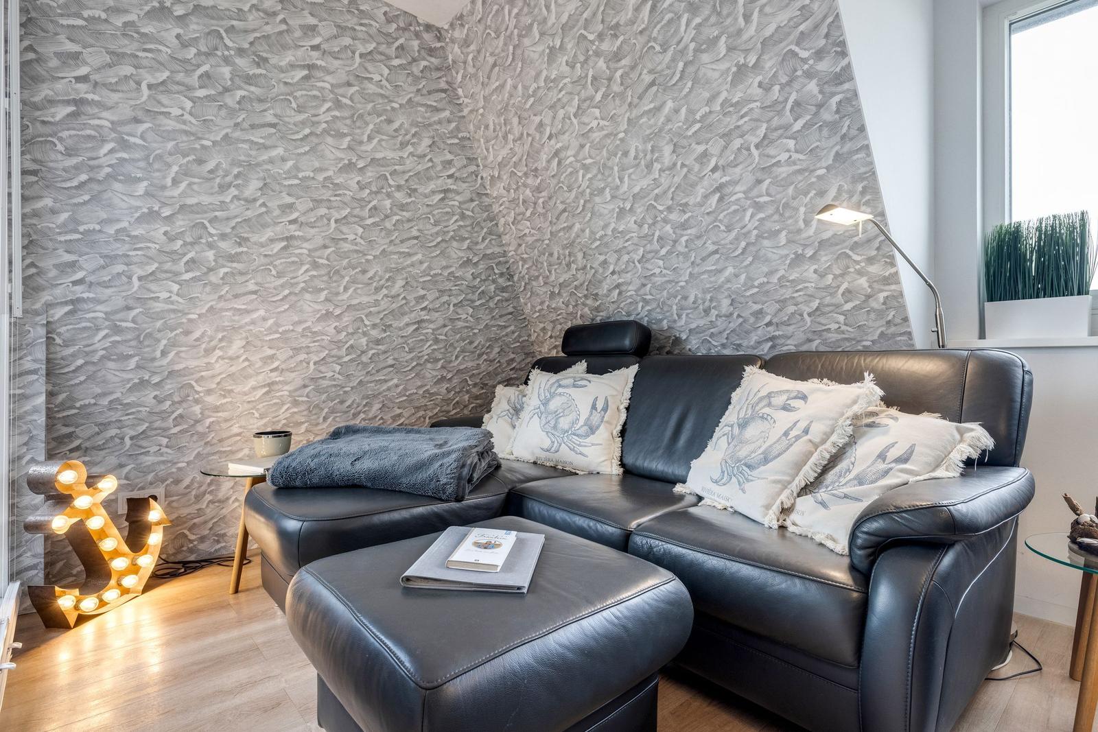 Schwarzes Ledersofa mit Kissen und Beistelltisch vor texturiertem Wandpaneel.