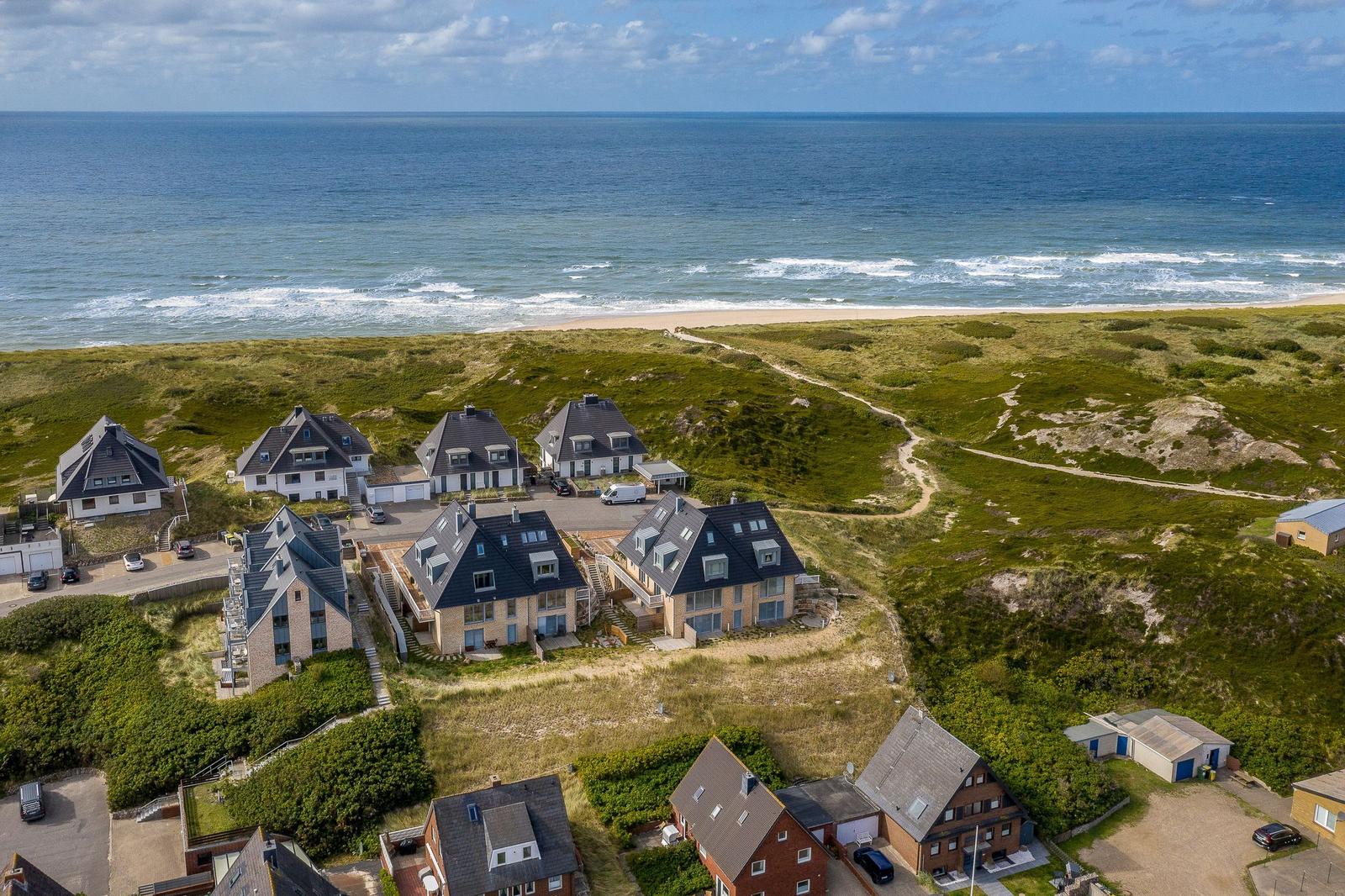 Strandnahe Häuser mit Grünflächen und Meerblick.