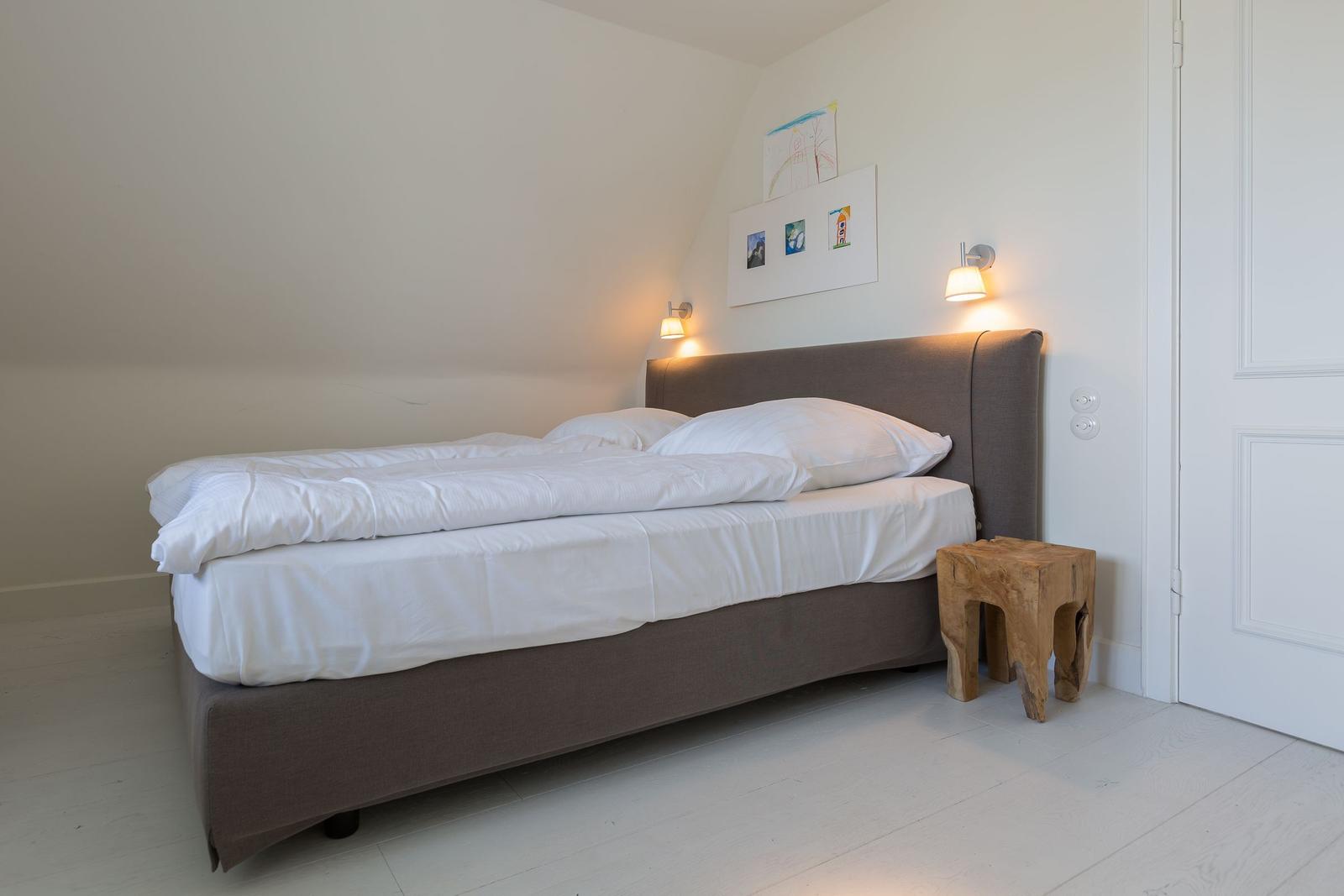 Schlafzimmer mit Bett, Nachttisch und Wandlampen.