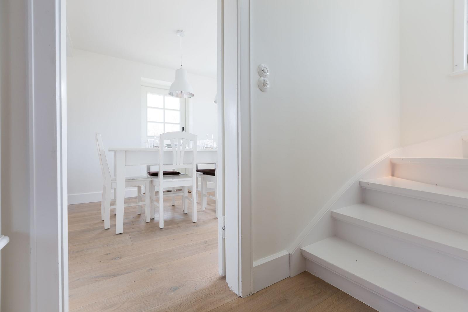 Treppe führt zu einer Treppe mit weißem Tisch und Stühlen im Hintergrund.