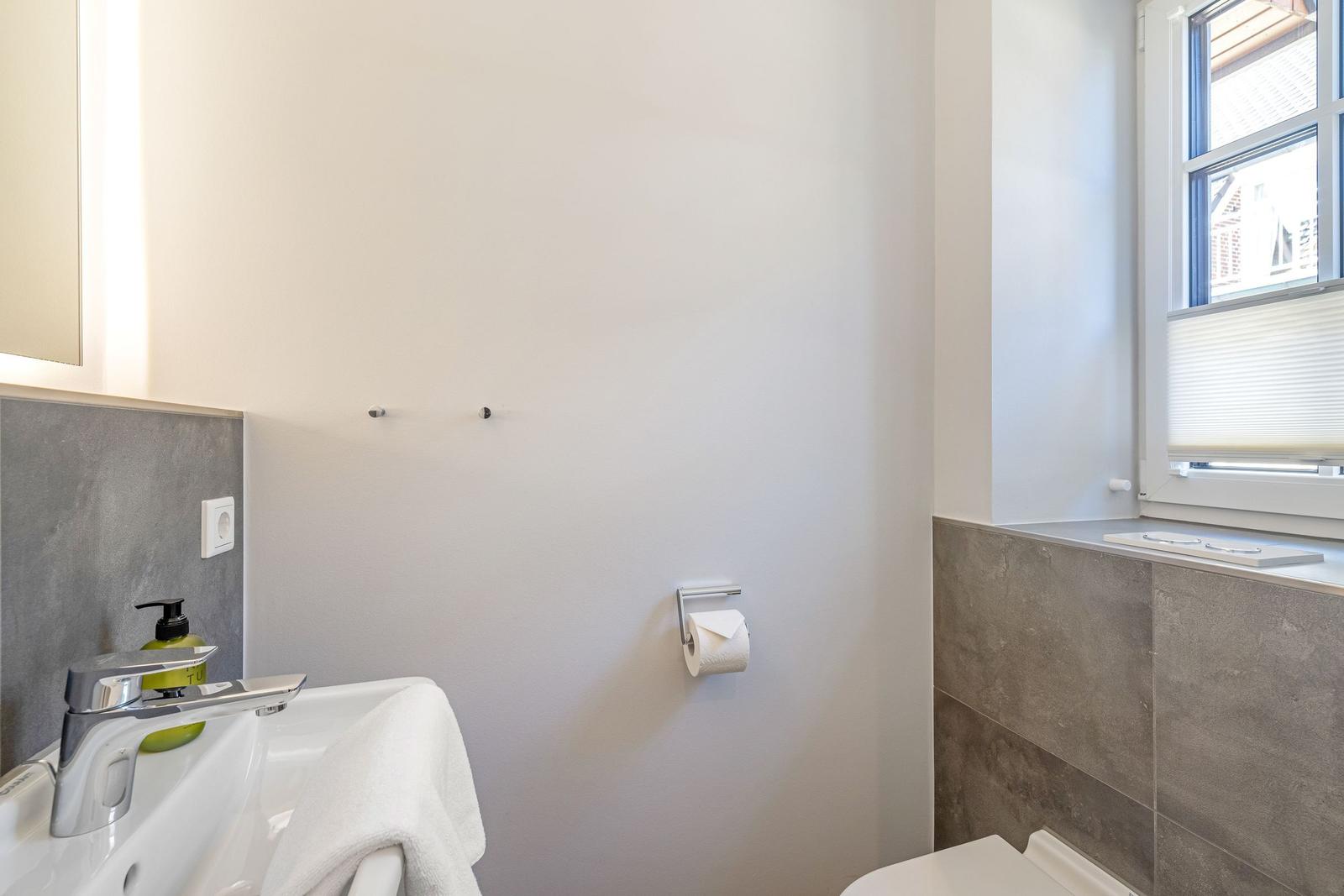 Badezimmer mit Waschbecken, Toilette und Fenster