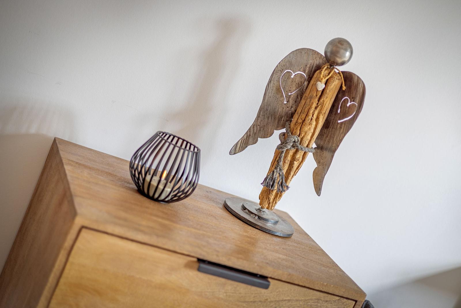 Holzengel mit Herzsymbol und Kerze auf einem Schrank