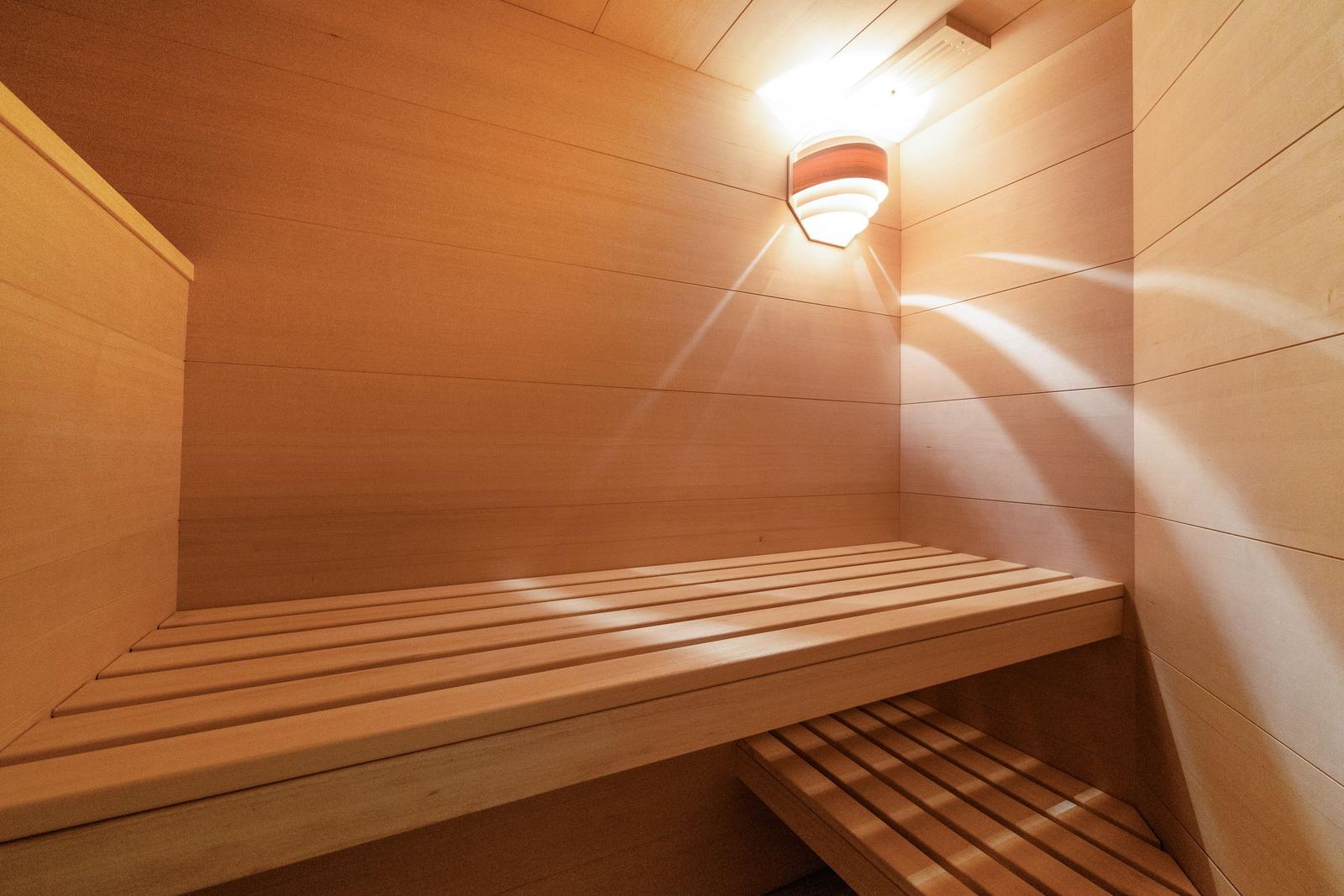 Sauna mit Holzbank und Wandbeleuchtung.