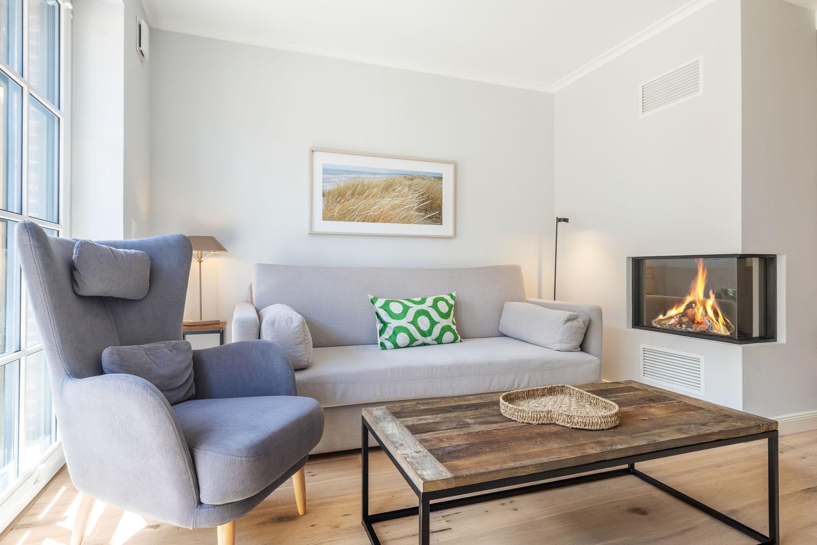 Wohnzimmer mit Sofa, Sessel, Kamin und Holztisch.
