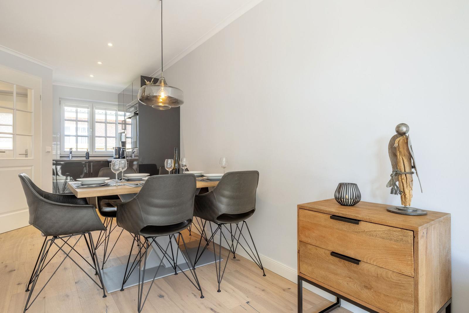 Esszimmer mit Holztisch, grauen Stühlen und moderner Hängelampe.