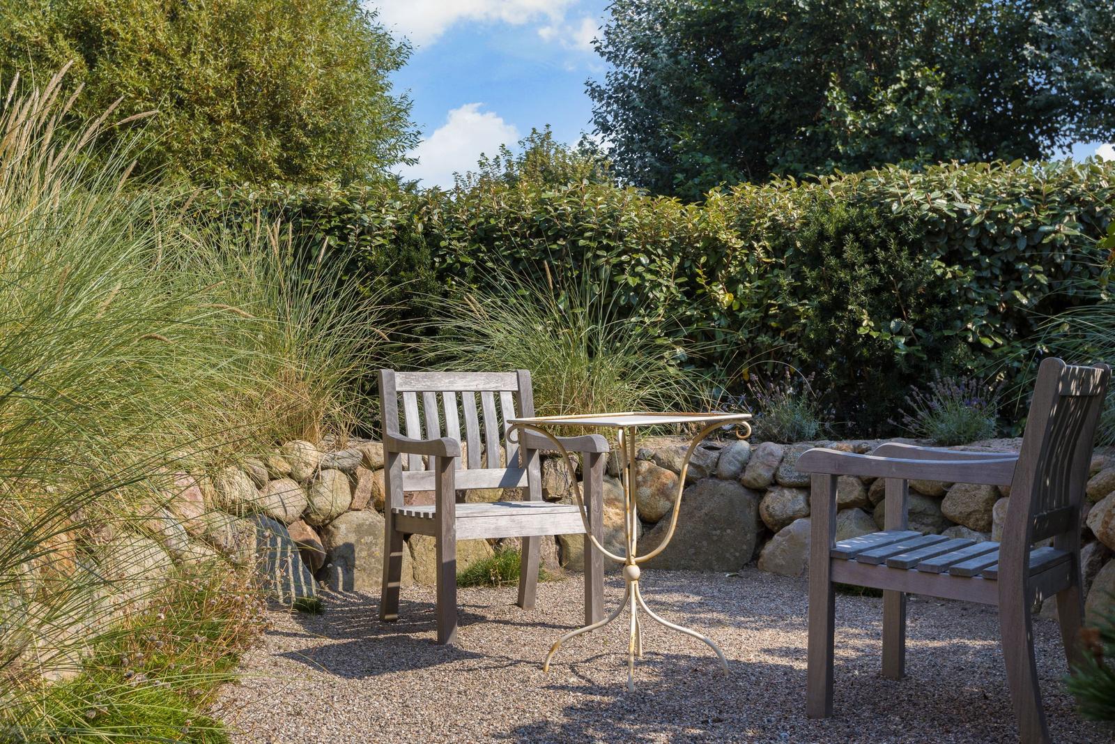 Garten mit zwei Holzstühlen und Tisch auf Kies