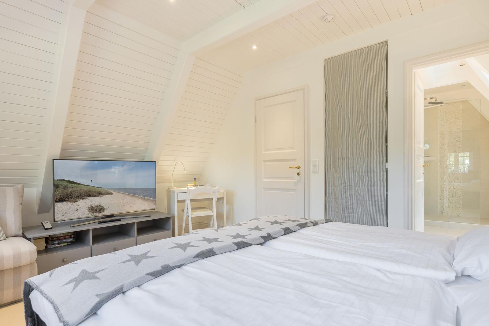 Schlafzimmer mit Dachschrägen, TV und Blick in Bad