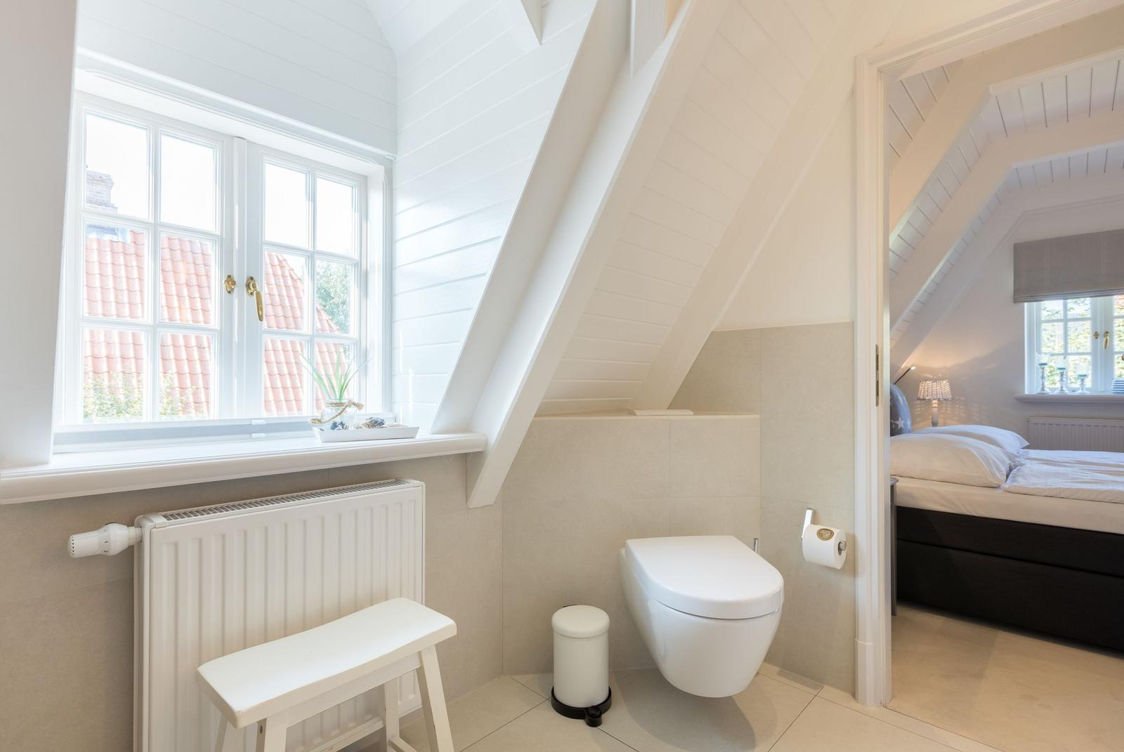 Sanitärzimmer mit Toilette und Fenster. Durchgang zur Schlafzimmer.
