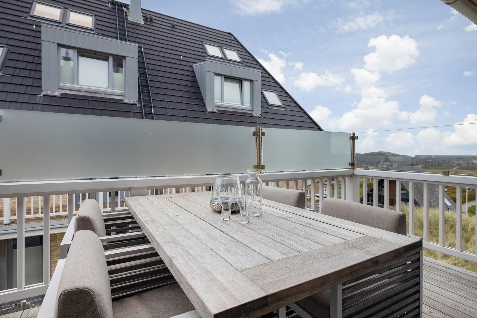 Terrasse mit Tisch und Stühlen, Blick auf Dach und Landschaft.