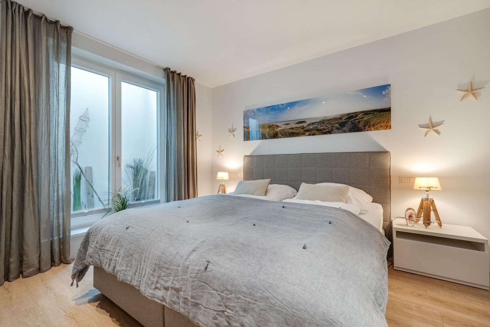 Schlafzimmer mit großem Bett, Fenster und Wandbild.