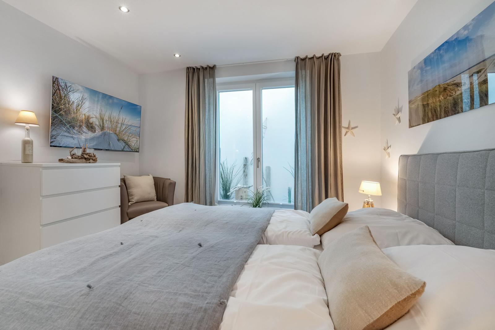 Schlafzimmer mit Bett, Schrank und Fenster zur Aussicht.